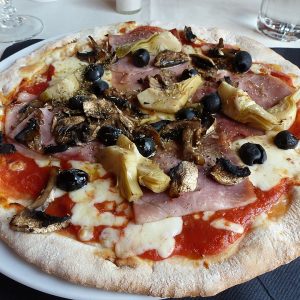 Pizza Capricciosa mit Schinken, Artischocken, Pilzen und Oliven - Pizzeria Bella
